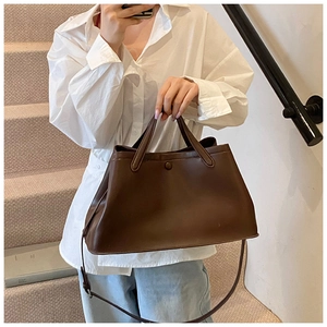 Detailed view of caramel brown leather bucket bag with top handles and shoulder strap