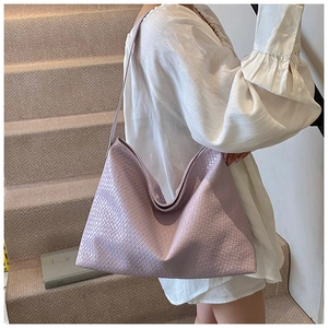 Detail of lavender woven leather tote bag with Intrecciato pattern on a model shoulder