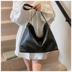 Detail of black woven leather shoulder bag with glossy texture and large capacity
