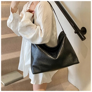 Close-up of black woven leather tote bag texture on female model in white shirt
