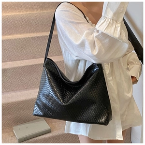 Detail of black woven texture on a large hobo shoulder bag with glossy finish