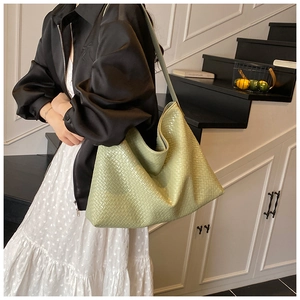 Detail of light green woven tote bag carried by model in a French retro vintage setting