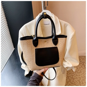 Detail of woven straw tote bag featuring black leather trim and handle with a pocket