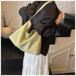 Detail of the light green hand-woven tote bag showing the wide strap and texture