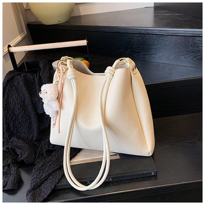 Détail du sac seau en cuir crème avec anses en corde et charmant ours en peluche