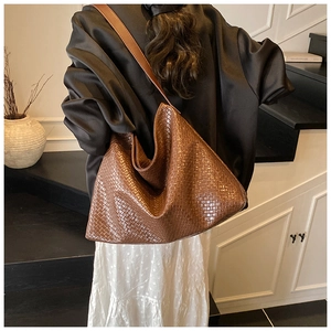 Detailed close-up of brown woven tote bag texture and smooth leather shoulder strap