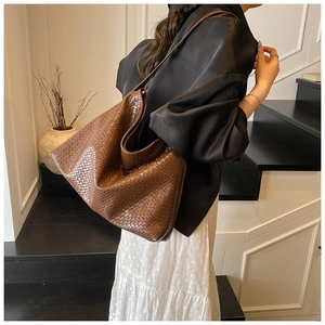 Detailed close-up of dark brown woven tote bag texture and slim shoulder strap