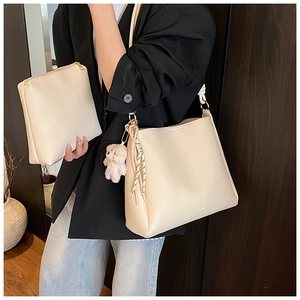 Détail du sac seau blanc crème avec texture grainée, pochette et breloque ours