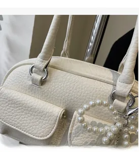 Detail of white lychee leather texture and silver ring hardware with pearl charm