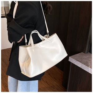 Detailed view of a white minimalist tote bag styled with a professional suit