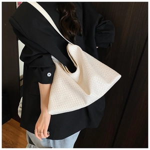 Detail of white woven leather tote bag showing intricate checkered pattern and wide strap