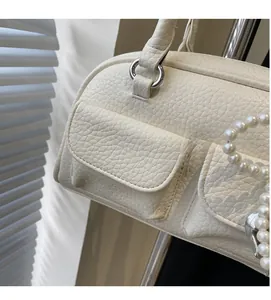 Detail of off-white leather pillow bag showing lychee grain texture and pearl chain