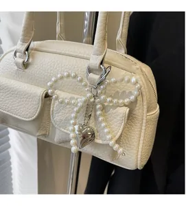Detail view of white lychee textured bag with pearl bow and silver heart pendant