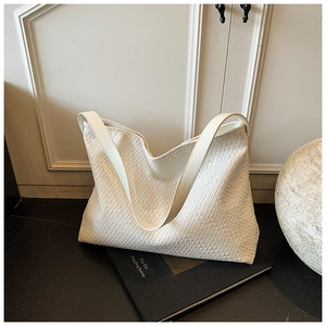 Close-up of white woven tote bag texture showing detailed soft craftsmanship and wide strap