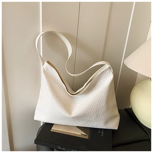Close-up of white tote bag showing detailed woven leather texture on a minimalist stand