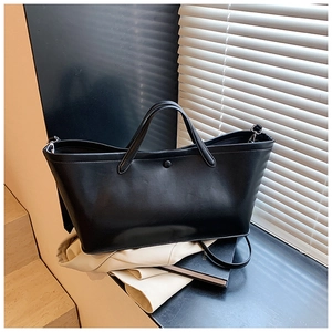 Detail of black tote bag featuring a smooth finish and adjustable shoulder strap
