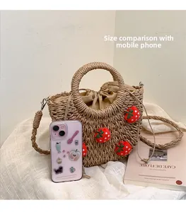 Detailaufnahme der Strohhandtasche mit Plüsch-Erdbeeren und Handy zum Größenvergleich