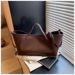 Detail view of large dark brown matte leather tote bag with soft texture and sturdy base