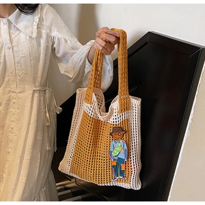 Nahaufnahme der gelben und beigen Häkeltasche mit detaillierter Comic-Stickerei