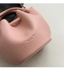Vue détaillée du cuir grainé rose et du logo embossé sur le sac seau moderne