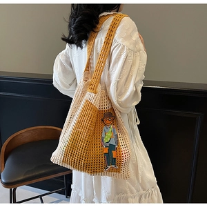 Detail der handgewebten Netztasche mit gelbem Kontrast und Cartoon-Patch am Modell