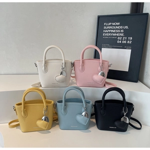 Detailed view of mini litchi leather bucket bags with heart charms in five colors