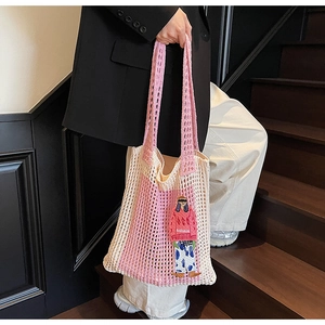 Detail der rosa gestrickten Netztasche mit modischem Aufnäher auf einer Holztreppe