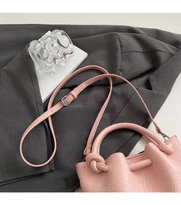 Sac seau en cuir grainé rose avec poignée nouée et bandoulière réglable élégante