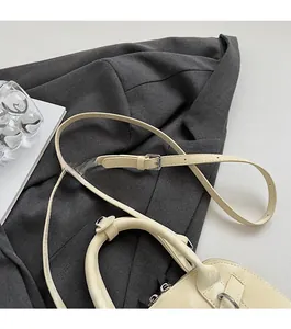 Détail de la bandoulière réglable en similicuir beige avec boucle en métal argenté du sac