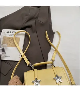 Detail of light yellow mini backpack with silver star studs and a plush bear charm