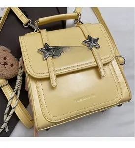 Detail of cream crossbody bag with silver star ornament and brown teddy bear charm