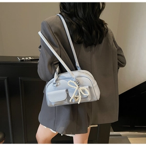 Detail of light blue boston bag with pearl bow and heart pendant on lychee leather