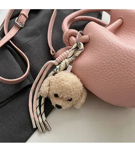 Détail du pendentif chien en peluche et de la lanière tressée sur un sac rose
