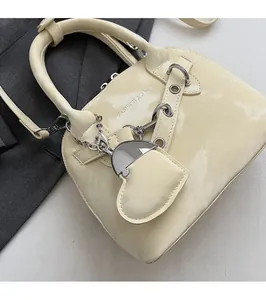 Détail du sac à main en cuir verni beige avec poignée et pendentif en forme de cœur