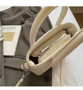 Detailed view of the smooth metal zipper and premium lychee texture on the beige bucket bag