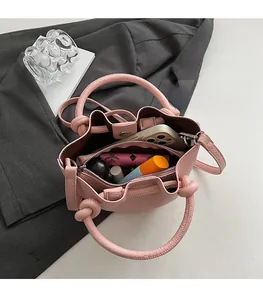 Vue de dessus de l'intérieur du sac seau en cuir rose avec compartiment zippé et cosmétiques