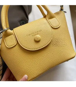 Gros plan du sac à main jaune texture litchi avec ferrures et fermeture à pression