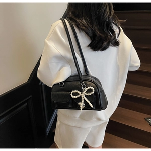 Detail of black Boston bag with lychee grain leather and pearl bow charm accessory