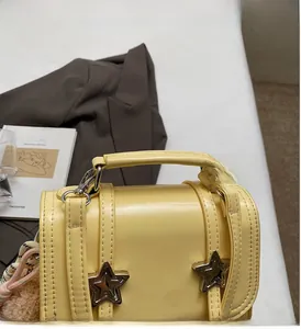 Detail of bright yellow leather handbag featuring silver star studs and reinforced handle