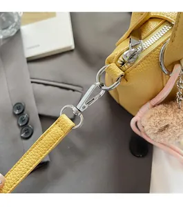 Détail d'un sac à main jaune texture litchi avec boucle argentée et breloque ours