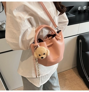 Pink bucket bag with lychee texture featuring a cute dog pendant and adjustable strap