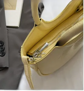 Detail of smooth silver zipper and natural leather texture on cream crossbody bag