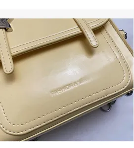 Close-up of cream yellow faux leather bag featuring silver star hardware and fine stitching