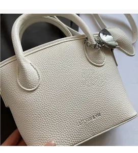 Detail of white litchi pattern leather handbag with silver heart charm and crossbody strap