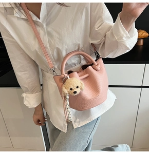 Detail of pink lychee leather bucket bag with teddy charm and gold lettering branding
