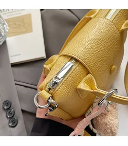 Gros plan sur la fermeture éclair en métal argenté et le cuir jaune grainé du sac à main