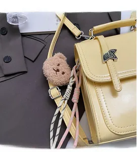 Close-up of yellow PU leather backpack with star metal buckle and plush bear charm