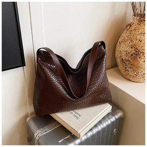 Detailed close-up of dark brown woven tote bag with intricate texture and broad strap