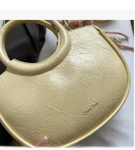 Detailed close-up of light yellow bucket bag featuring crinkled leather texture and round handle