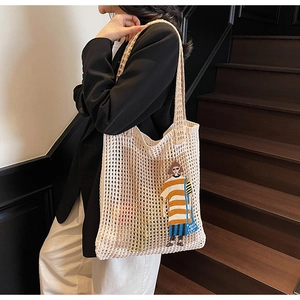 Detailansicht der cremefarbenen Häkeltasche mit bunter Cartoon-Mädchen-Stickerei